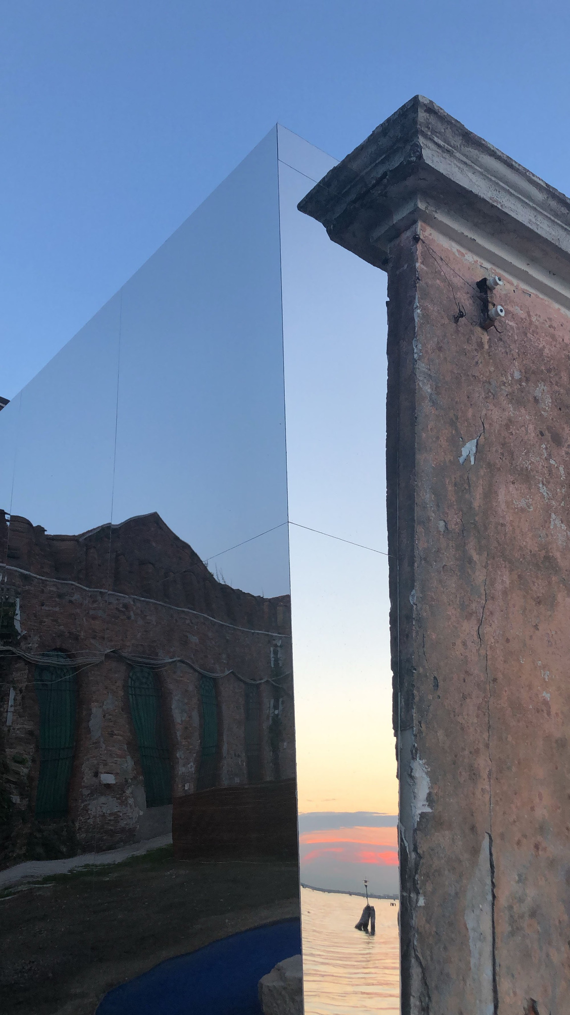 Facciata riflettente al tramonto con scorcio lagunare