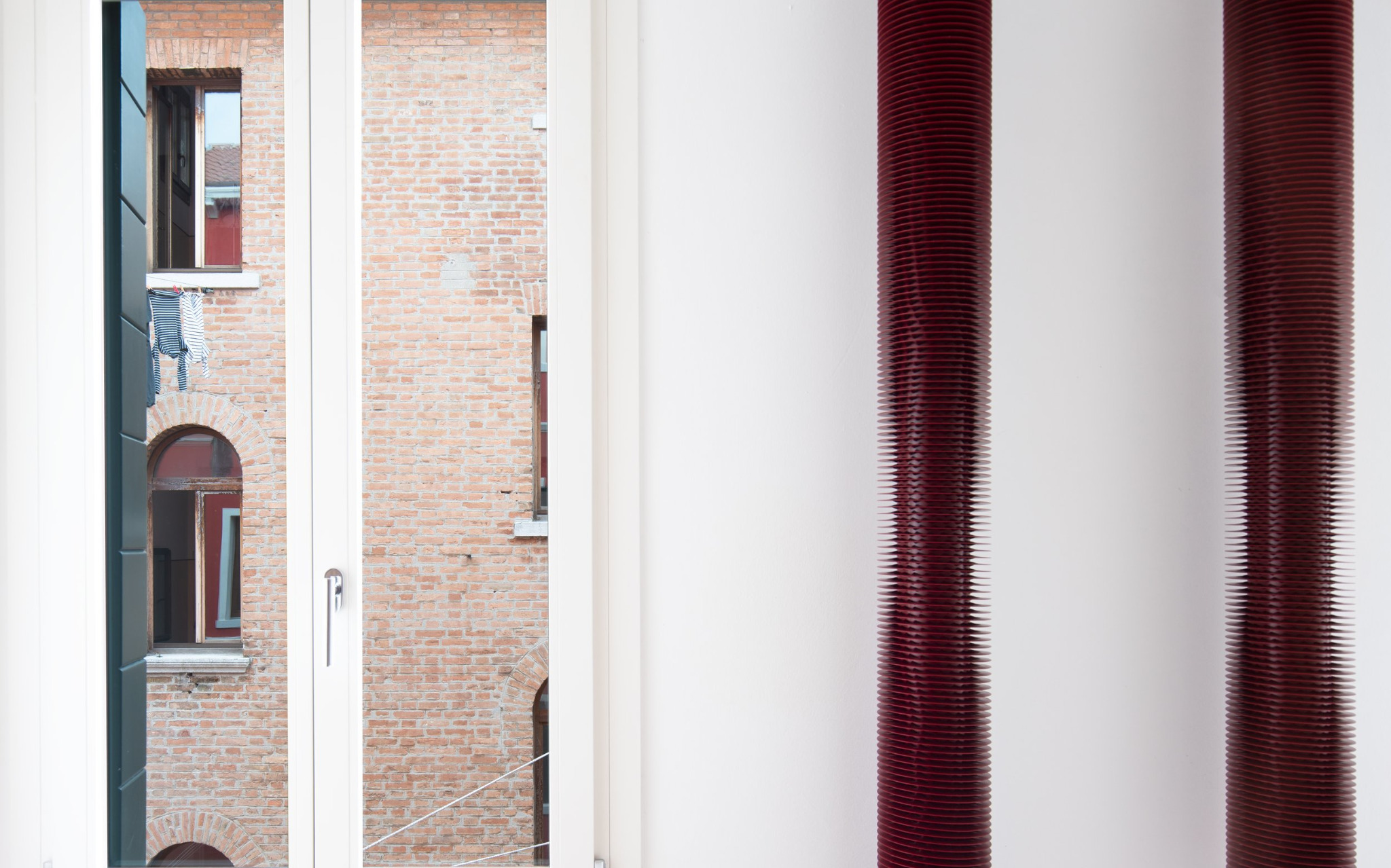 Radiatori rossi vicino a finestra con vista su edificio in mattoni